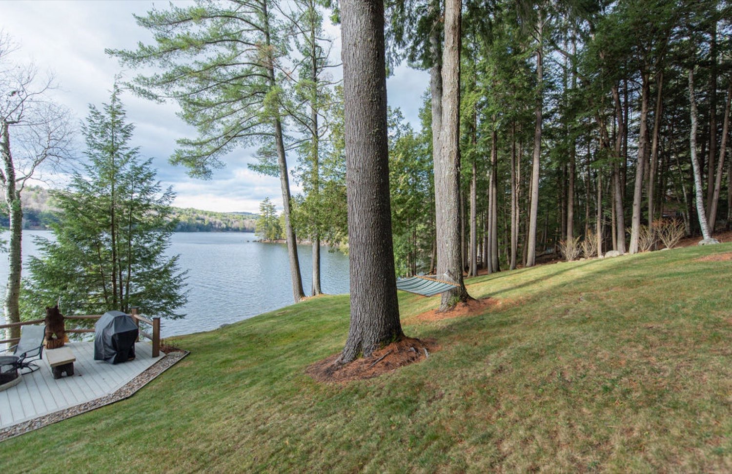 A hammock strung between tall pines above the dock and waterfront deck at Camp Sunnyside on Friends Lake.